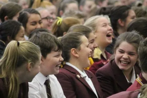 group of school kids laughing at motivational speaker